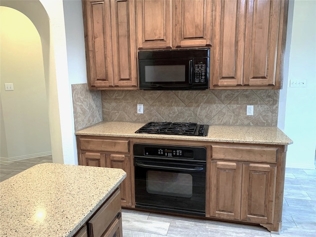 11711 Corsicana Dr, Frisco, TX 75035 - kitchen with black appliances, arched walkways, backsplash, light stone counters, and baseboards
