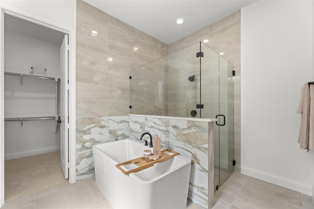 2016 Morris St, Rockwall, TX 75087 - bathroom with a stall shower, a walk in closet, tile patterned flooring, a soaking tub, and tile walls