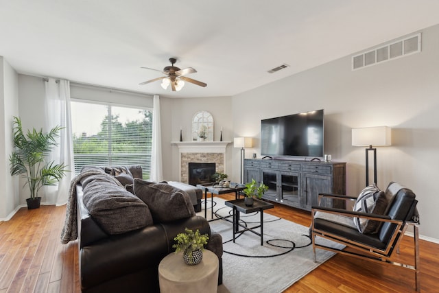11487 Balcones Dr, Frisco, TX 75033 - living room with a glass covered fireplace, ceiling fan, wood finished floors, and baseboards