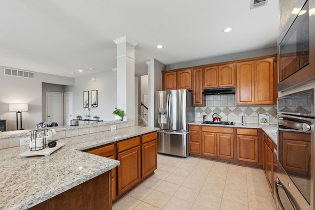 11487 Balcones Dr, Frisco, TX 75033 - kitchen with stainless steel appliances, under cabinet range hood, light stone counters, light tile patterned floors, and tasteful backsplash