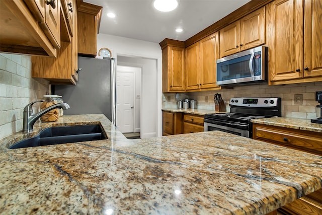674 Milam Rd, Van Alstyne, TX 75495 - kitchen with appliances with stainless steel finishes, a sink, brown cabinets, and light stone countertops
