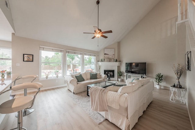 5309 Chatsworth Ln, Fort Worth, TX 76244 - living area featuring a ceiling fan, light wood finished floors, a glass covered fireplace, high vaulted ceiling, and baseboards
