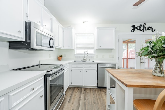 13063 Whiterock Rd, Mabank, TX 75147 - kitchen with appliances with stainless steel finishes, a sink, white cabinetry, light wood-style flooring, and healthy amount of natural light