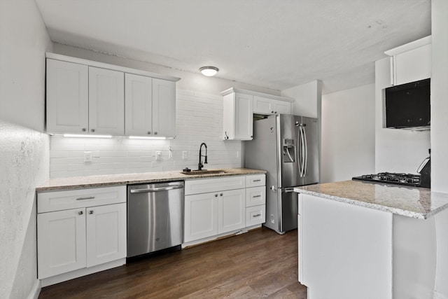 5509 Cloverdale Dr, Fort Worth, TX 76134 - kitchen with appliances with stainless steel finishes, a sink, decorative backsplash, white cabinets, and dark wood-style flooring