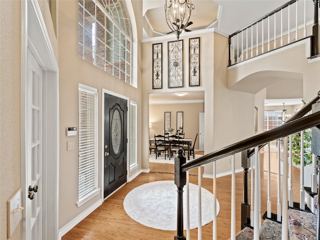1308 Crown Point Rd, Mckinney, TX 75072 - entrance foyer with a chandelier, baseboards, a towering ceiling, wood finished floors, and arched walkways