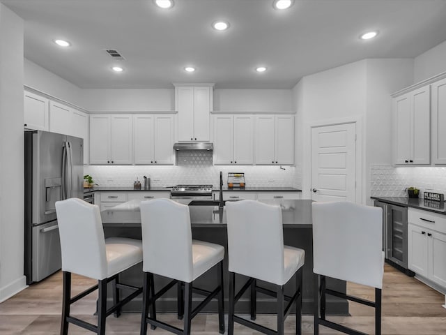 1708 Jamestown Dr, Forney, TX 75126 - kitchen with appliances with stainless steel finishes, under cabinet range hood, beverage cooler, dark countertops, and backsplash