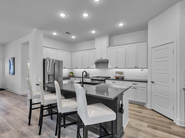 1708 Jamestown Dr, Forney, TX 75126 - kitchen featuring under cabinet range hood, stainless steel appliances, a kitchen breakfast bar, decorative backsplash, and light wood-style flooring