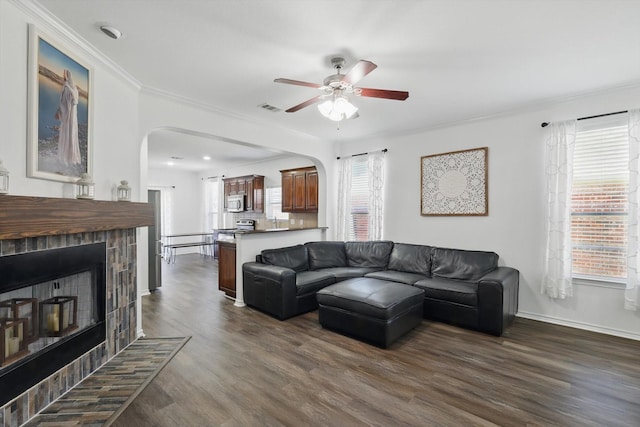 544 Baverton Ln, Fort Worth, TX 76052 - living area with arched walkways, a fireplace, ornamental molding, ceiling fan, and dark wood-style flooring
