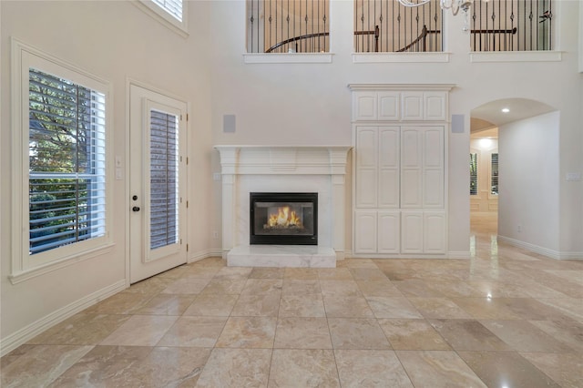 5622 Braemar Dr, Frisco, TX 75034 - unfurnished living room featuring baseboards, a towering ceiling, arched walkways, and a glass covered fireplace