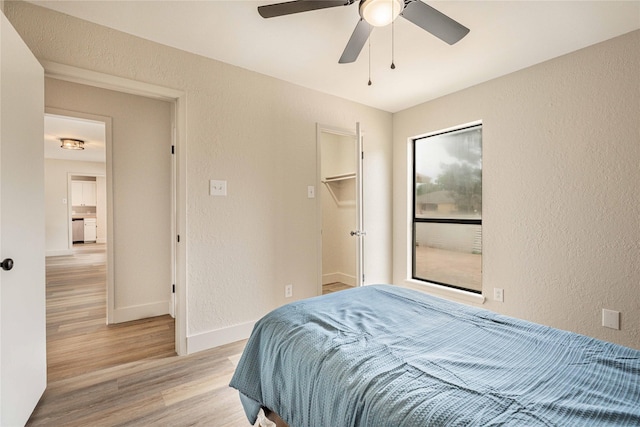4702 Pamela Dr, Abilene, TX 79606 - bedroom featuring a textured wall, light wood-style flooring, baseboards, a spacious closet, and a ceiling fan