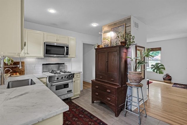 11202 Myrtice Dr, Dallas, TX 75228 - kitchen with stainless steel appliances, a sink, tasteful backsplash, light stone counters, and cream cabinets