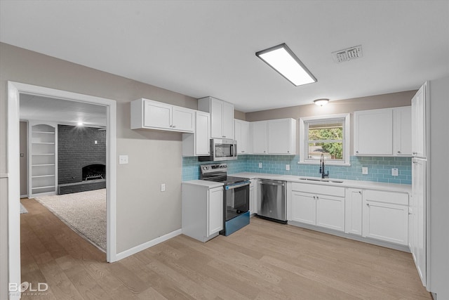 9312 Pine Grove St, Shreveport, LA 71118 - kitchen featuring appliances with stainless steel finishes, a sink, light wood finished floors, and white cabinetry