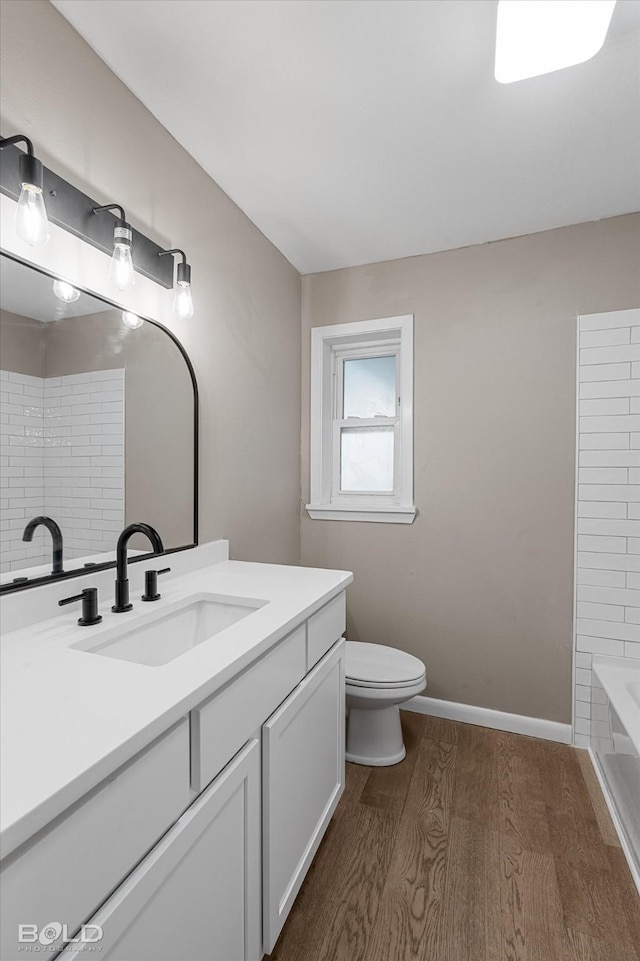 9312 Pine Grove St, Shreveport, LA 71118 - full bathroom with wood finished floors, vanity, a tub to relax in, toilet, and baseboards