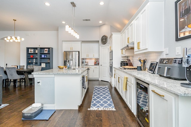 1502 Barley Ct, Forney, TX 75126 - kitchen with wine cooler, under cabinet range hood, appliances with stainless steel finishes, white cabinetry, and vaulted ceiling