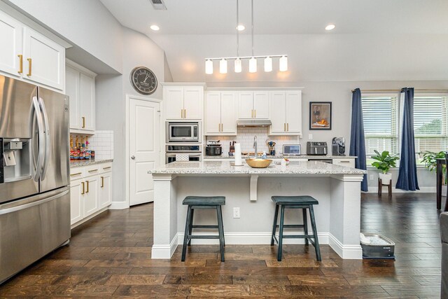 1502 Barley Ct, Forney, TX 75126 - kitchen with appliances with stainless steel finishes, under cabinet range hood, decorative backsplash, a breakfast bar, and white cabinets