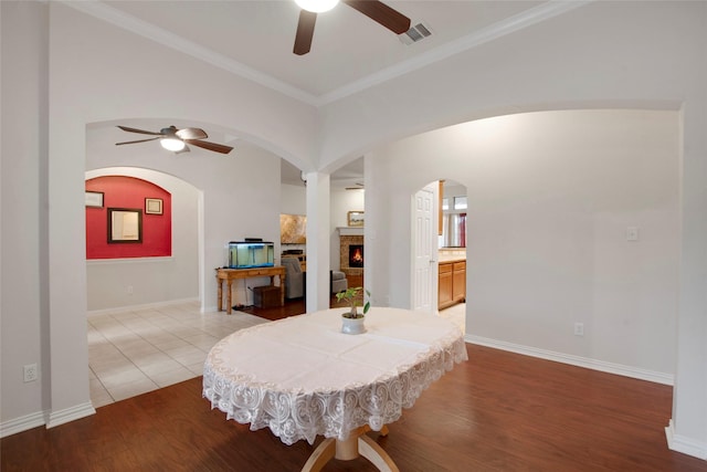 1212 Live Oak St, Royse City, TX 75189 - dining room with a ceiling fan, arched walkways, wood finished floors, a warm lit fireplace, and baseboards
