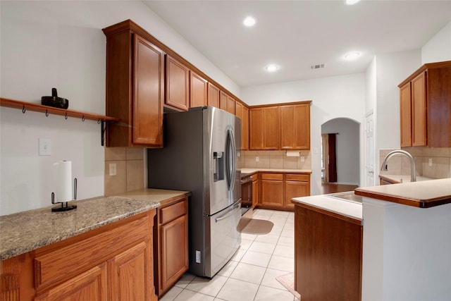 1212 Live Oak St, Royse City, TX 75189 - kitchen featuring stainless steel fridge with ice dispenser, decorative backsplash, arched walkways, light tile patterned floors, and light countertops