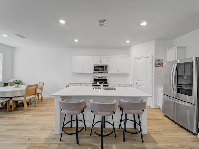316 Crossvine Way, Princeton, TX 75407 - kitchen featuring stainless steel appliances, light countertops, white cabinetry, an island with sink, and light wood finished floors