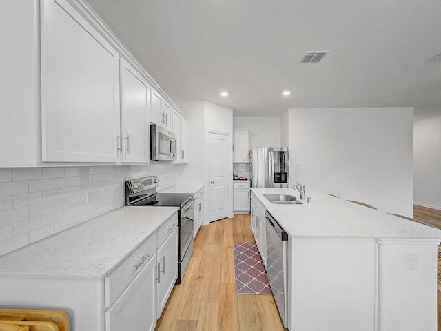 316 Crossvine Way, Princeton, TX 75407 - kitchen featuring stainless steel appliances, a sink, an island with sink, light wood finished floors, and white cabinetry