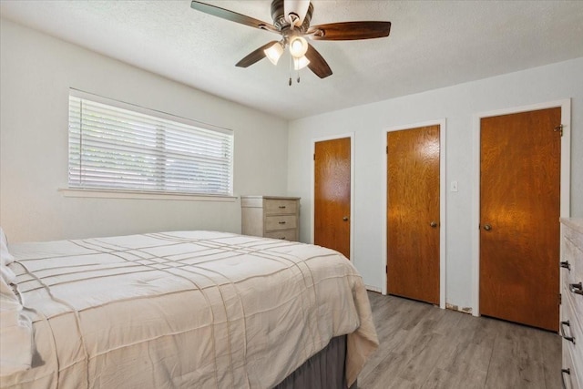 1004 Fairway Ln, Mexia, TX 76667 - bedroom featuring light wood finished floors, two closets, ceiling fan, and a textured ceiling