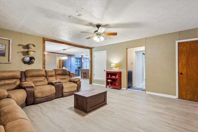 1004 Fairway Ln, Mexia, TX 76667 - living room featuring light wood finished floors, a textured ceiling, a ceiling fan, and baseboards