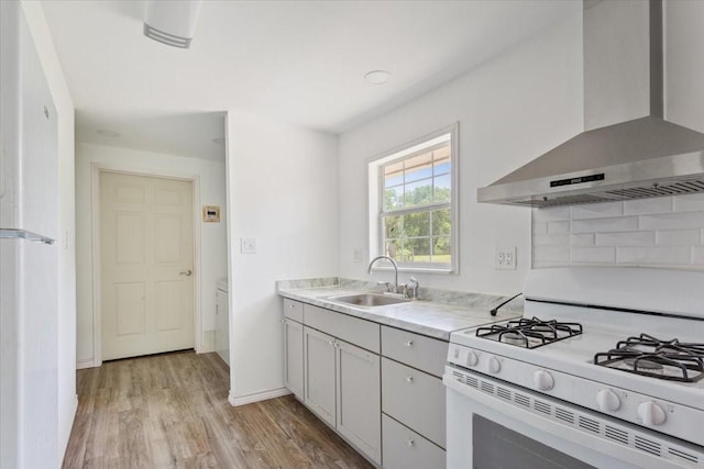 413 Houghton Ave, Marlin, TX 76661 - kitchen with white appliances, wall chimney range hood, a sink, light wood finished floors, and light countertops