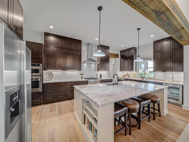 6362 Belz Rd, Sanger, TX 76266 - kitchen with stainless steel appliances, wall chimney range hood, a sink, a center island with sink, and light wood finished floors