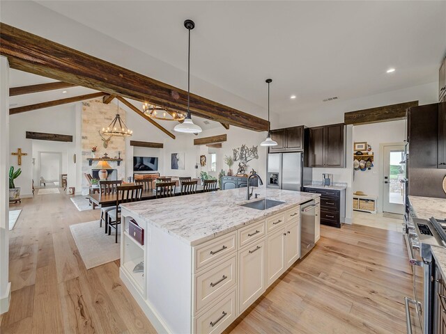 6362 Belz Rd, Sanger, TX 76266 - kitchen featuring stainless steel appliances, a sink, light wood-type flooring, light stone counters, and an island with sink