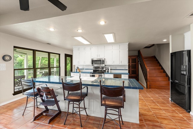 7016 Fm 3054, Malakoff, TX 75148 - kitchen featuring stainless steel appliances, tile countertops, white cabinets, a kitchen breakfast bar, and recessed lighting
