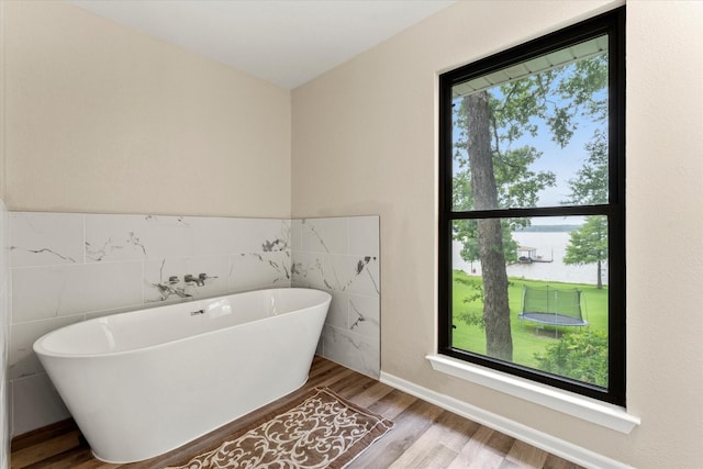7016 Fm 3054, Malakoff, TX 75148 - full bathroom featuring tile walls, wood finished floors, a freestanding bath, and a wainscoted wall