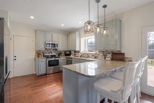 40 Pebble Beach St, Abilene, TX 79606 - kitchen with stainless steel appliances, a peninsula, a sink, tasteful backsplash, and dark wood-style floors