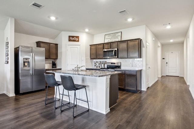 2118 Brisbon St, Fate, TX 75189 - kitchen with stainless steel appliances, tasteful backsplash, dark brown cabinets, stone countertops, and a kitchen bar