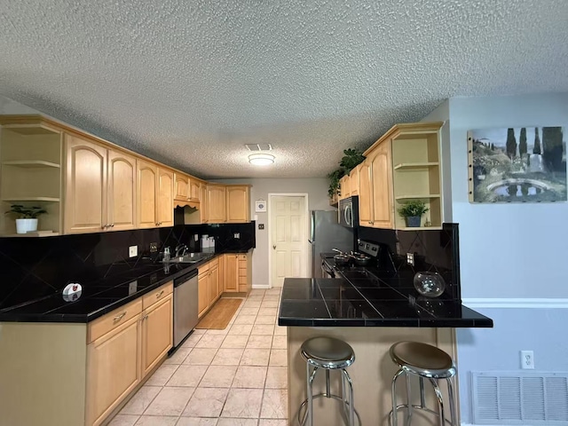 112 Plainview Dr, Wylie, TX 75098 - kitchen featuring open shelves, appliances with stainless steel finishes, a breakfast bar, a sink, and a peninsula