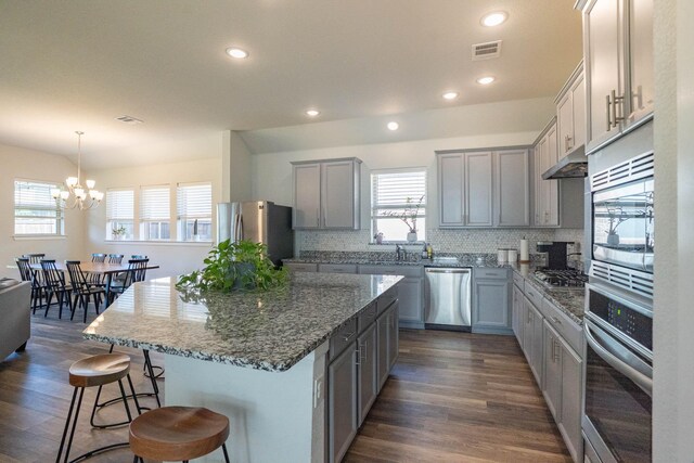 4714 Crestwood Dr, Haltom City, TX 76137 - kitchen with appliances with stainless steel finishes, stone counters, a breakfast bar area, tasteful backsplash, and dark wood finished floors