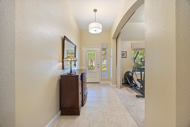 676 Woodland Way, Rockwall, TX 75087 - foyer entrance with arched walkways, a textured wall, light tile patterned floors, baseboards, and light colored carpet