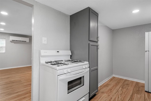 2511 S 7th, Waco, TX 76706 - kitchen featuring white gas range, gray cabinets, a wall mounted air conditioner, light wood-style floors, and recessed lighting