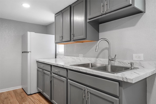 2511 S 7th, Waco, TX 76706 - kitchen featuring gray cabinets, a sink, light wood-type flooring, light countertops, and freestanding refrigerator
