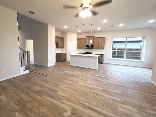 7749 Gatevine Ave, Joshua, TX 76058 - kitchen featuring open floor plan, stainless steel microwave, wood finished floors, ceiling fan, and light countertops
