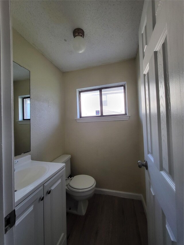 1906 N 4th St, Killeen, TX 76541 - half bath featuring a textured ceiling, toilet, wood finished floors, plenty of natural light, and vanity
