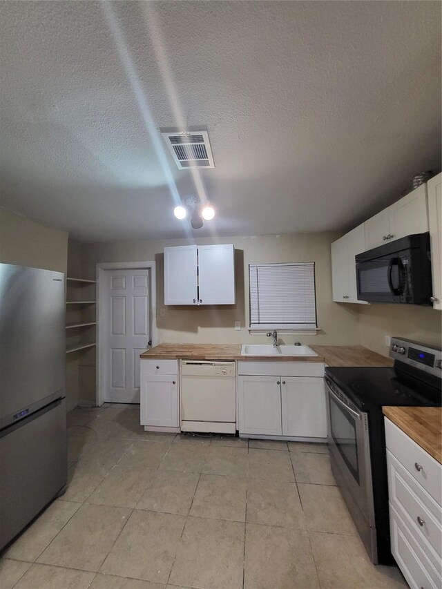 1906 N 4th St, Killeen, TX 76541 - kitchen featuring appliances with stainless steel finishes, wooden counters, a textured ceiling, and white cabinetry