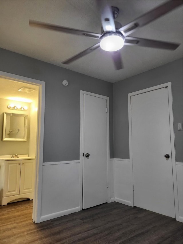 1906 N 4th St, Killeen, TX 76541 - unfurnished bedroom featuring a wainscoted wall, dark wood-style floors, ensuite bath, ceiling fan, and a sink