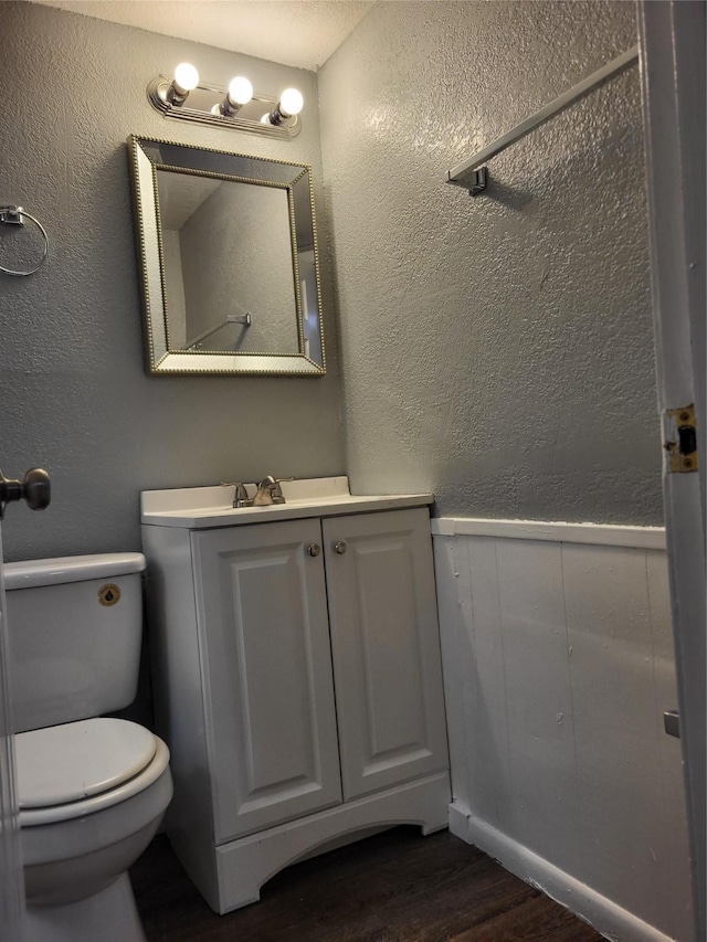 1906 N 4th St, Killeen, TX 76541 - bathroom featuring wood finished floors, toilet, vanity, wainscoting, and a textured wall