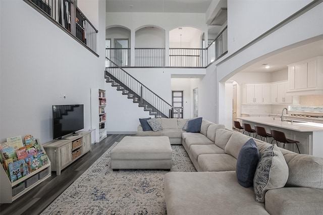 12959 Averi Ln, Farmers Branch, TX 75234 - living room with a high ceiling, dark wood-style flooring, arched walkways, stairs, and baseboards