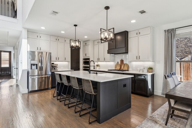 5221 Sylvan Shores Dr, Frisco, TX 75036 - kitchen featuring appliances with stainless steel finishes, a chandelier, dark wood finished floors, light countertops, and a center island with sink