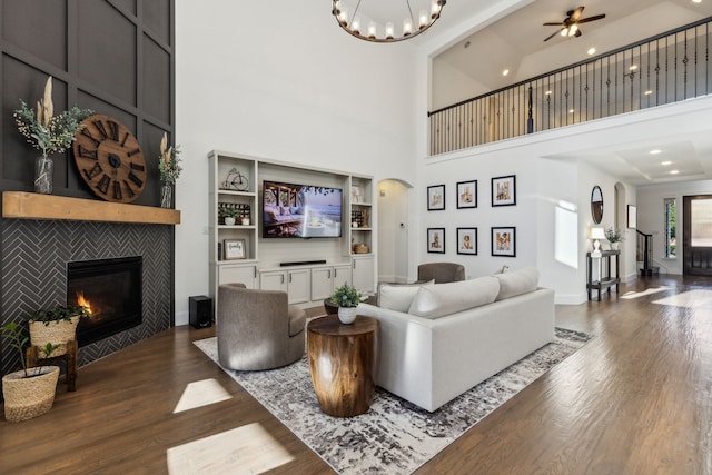5221 Sylvan Shores Dr, Frisco, TX 75036 - living area featuring wood finished floors, arched walkways, a tiled fireplace, a towering ceiling, and a ceiling fan