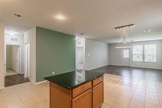 2409 Buelingo Ln, Fort Worth, TX 76131 - kitchen with light tile patterned floors, a center island, baseboards, open floor plan, and brown cabinetry