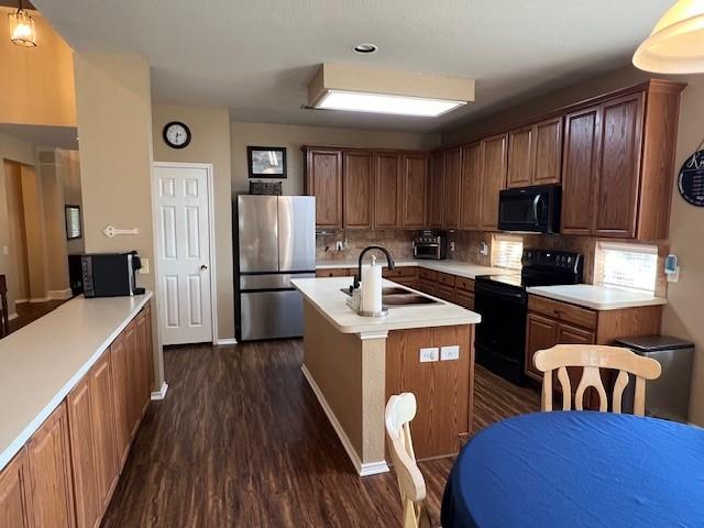 1275 Calistoga Dr, Rockwall, TX 75087 - kitchen with black appliances, a sink, dark wood-style floors, light countertops, and tasteful backsplash