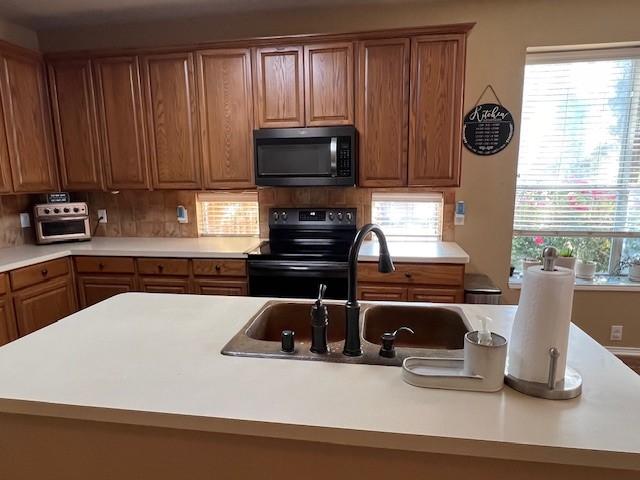 1275 Calistoga Dr, Rockwall, TX 75087 - kitchen featuring black appliances, a sink, light countertops, and brown cabinetry
