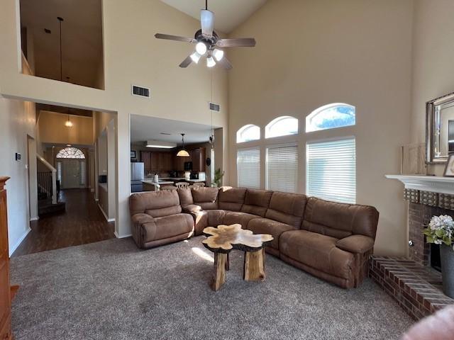 1275 Calistoga Dr, Rockwall, TX 75087 - living area featuring stairs, a ceiling fan, high vaulted ceiling, a brick fireplace, and carpet flooring