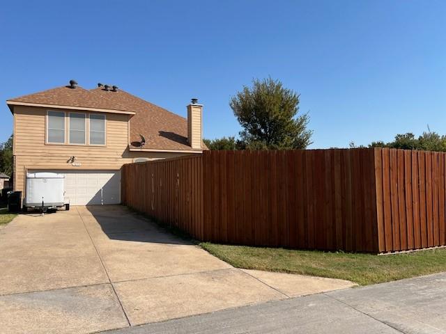 1275 Calistoga Dr, Rockwall, TX 75087 - view of property exterior with concrete driveway, an attached garage, and a chimney